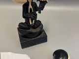a figurine of a man in a tuxedo with a flower in his hand