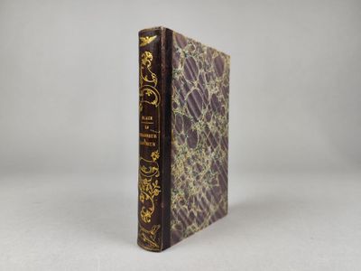 un livre marron orné d'une inscription dorée, posé sur une surface blanche