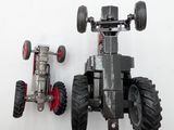 a toy tractor and a toy car on a white surface
