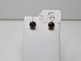 une paire de boucles d'oreilles à clous noires et dorées posées sur un présentoir blanc