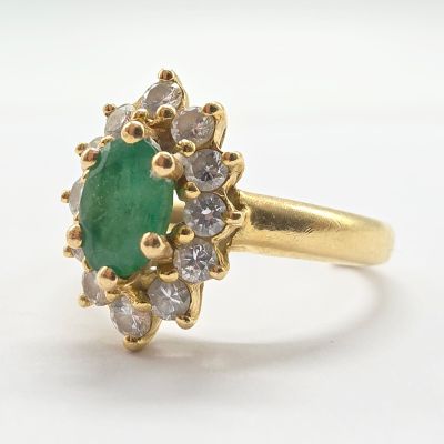 un gros plan d'une bague en or sertie d'une pierre verte entourée de diamants blancs