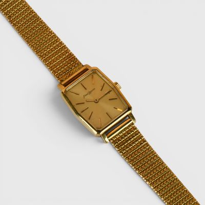 gros plan d'une montre en or sur une surface blanche