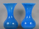 pair of blue glass vases sitting on top of a table