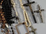 rosary and other religious items are displayed on a white surface