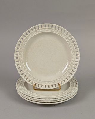 three white dinner plates with gold rims on a gray surface