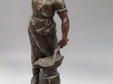 bronze statue of a blacksmith holding a hammer and anvil