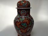 un vase rouge muni d'un couvercle, posé sur une table