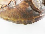 a statue of a bird sitting on top of a piece of wood
