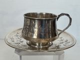 une tasse et une soucoupe en argent posées sur un plateau en argent