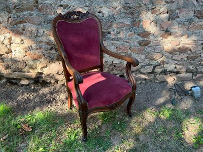 une chaise rouge posée devant un mur de pierre