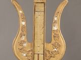 a gold clock with a thermometer on top of it