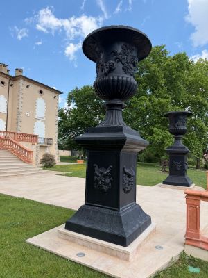 a black urn sitting in the middle of a grassy area