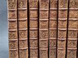 several old books are stacked on top of each other on a gray surface