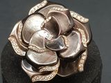 silver and gold rose ring with diamonds on a black surface