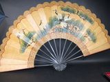 a fan with a painting on it sitting on a table