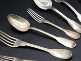 six silver spoons and a fork on a black surface