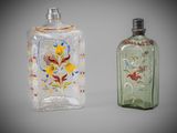 two glass bottles with designs on them sitting next to each other