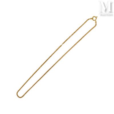 un collier en or avec une longue chaîne sur fond blanc