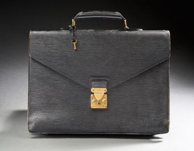 an old black briefcase sitting on top of a white table