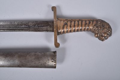 a knife with a lion head on it next to a tube