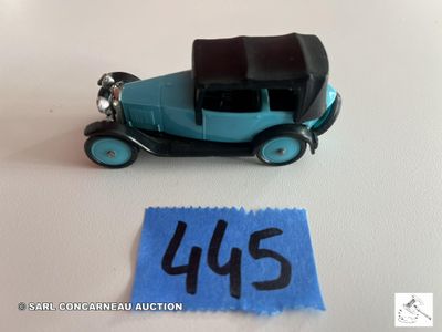 une petite voiture miniature posée à côté d'une feuille de papier bleue