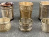four different types of silver cups and spoons on a table