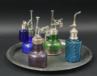 five different colored glass bottles sitting on a silver tray