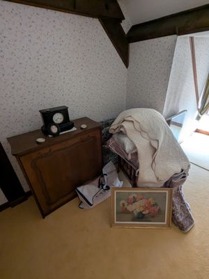 une photo d'une chambre avec un lit et un tableau posé par terre