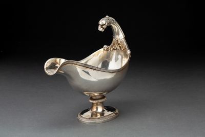 une saucière ancienne en métal argenté, surmontée d'un oiseau