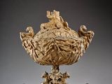 an image of a golden vase on a stand on a gray surface