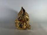 a gold figurine sitting on a white surface