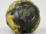 an old black and gold vase sitting on top of a white surface