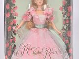 La poupée se trouve dans une boîte, vêtue d'une robe rose et d'un ruban à nouer.