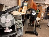 a fan sitting on a chair in a cluttered room