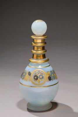 une bouteille en verre ornée d'un motif doré sur le goulot
