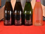 four bottles of wine are lined up on a red cloth