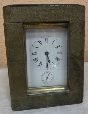 a small metal clock with roman numerals on the face