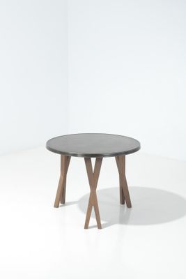 une table ronde avec deux pieds en bois et un plateau noir