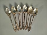 six silver spoons are lined up in a row on a table