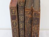 several old books are stacked on top of each other on a white surface