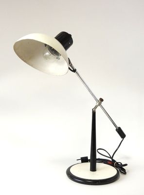 une photo d'une lampe de bureau en noir et blanc posée sur une surface blanche