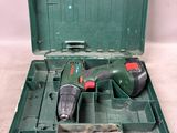 une boîte à outils verte contenant une perceuse et un foret