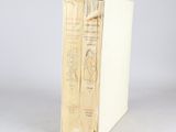 un vieux livre posé sur une table blanche à côté d'un mur gris