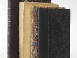 three old books are stacked on top of each other on a white surface