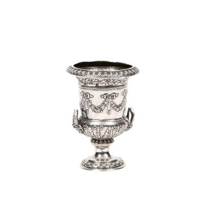 un vase en argent posé sur une surface blanche