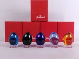 four glass eggs are lined up in a row in front of a red box