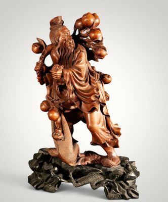 une statue en bois représentant un homme tenant un oiseau sur un rocher