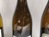 three bottles of wine are lined up on a white surface