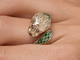 une image représentant la main d'une femme tenant une bague ornée d'un serpent