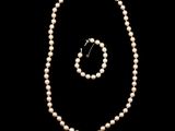a close up of a pearl necklace and earring on a black background